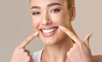 Happy Woman Pointing Fingers At Perfect Smile, Studio Shot