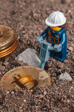 ANKARA, TURKEY. NOVEMBER 17, 2019. Woman Lego mini miner figurine working with pneumatic hammer and breaking rocks to uncover glowing bitcoin. Cryptocurrency, blockchain and mining concept.