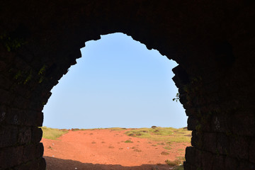 a view of the outside open area from inside a dark fort in India
