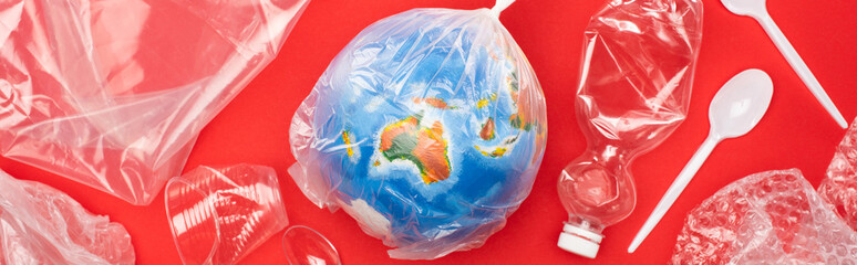Panoramic view of globe in plastic bag with garbage around on red, global warming concept