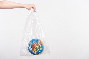 Cropped view of woman with outstretched hand holding globe in plastic bag isolated on white, global warming concept