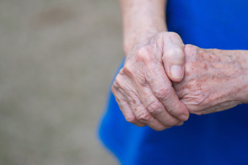 Close-up of elderly woman's hands joined together. Focus on hands wrinkled skin. Space for text. Health care concept