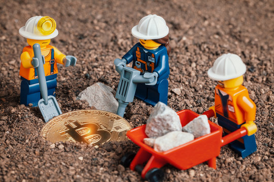 ANKARA, TURKEY. NOVEMBER 17, 2019. Lego mini miner figurines working with tools on ground to uncover bitcoin. Cryptocurrency, blockchain and mining concept.