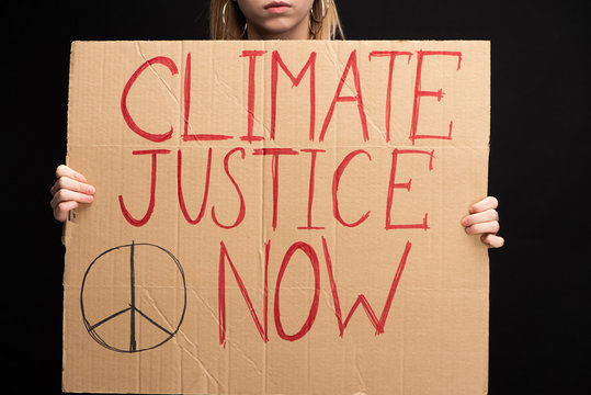 Partial View Of Blonde Woman Holding Placard With Climate Justice Now Lettering Isolated On Black, Global Warming Concept