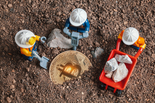 ANKARA, TURKEY. NOVEMBER 17, 2019. Lego mini miner figurines working with tools on ground to uncover bitcoin. Cryptocurrency, blockchain and mining concept.