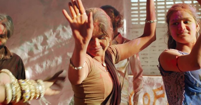 Crazy intoxicated Indian dancers male and female killing it on the dance floor as they dance in the summer sun rays and throw powdered colour in the air to celebrate the festival of Holi in India