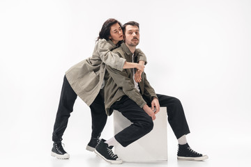 Embracing. Trendy fashionable couple isolated on white studio background. Caucasian woman and man posing in basic minimal stylish clothes. Concept of relations, fashion, beauty, love. Copyspace.