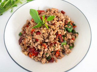 Stir fried basil with minced on a white plate,Thai food hot and spicy flavor. The ingredients are basil, garlic. Minced pork and Chili pepper,White background