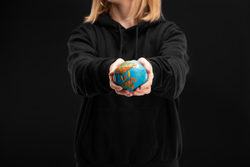Cropped view of woman with outstretched hands holding plasticine globe isolated on black, global warming concept