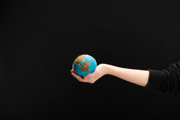 Partial view of woman with outstretched hand holding plasticine globe isolated on black, global warming concept