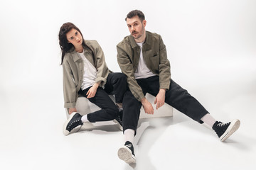 One whole. Trendy fashionable couple isolated on white studio background. Caucasian woman and man...