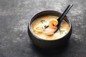 Tom yum, a spicy soup with coconut milk, shrimps and mushrooms. Traditional Japanese cuisine. Eastern cuisine. Soup on a dark background