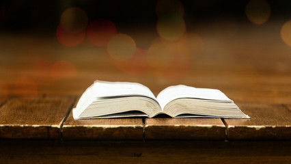 the book is laid on a red wooden floor with a bokeh background