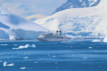 A cruise ship between the frozen coasts, icebergs and mountains of the Antarctic Peninsula. The...