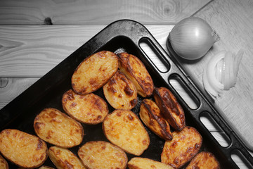 oven-baked potatoes on a wooden black-white table near onions