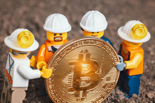 ANKARA, TURKEY. NOVEMBER 17, 2019. Group of Lego mini miner figurines holding shiny bitcoin together and posing. Cryptocurrency, blockchain and mining concept.