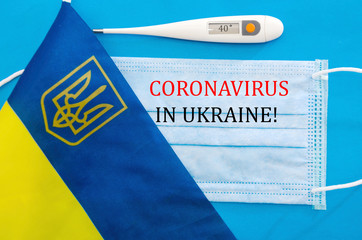 the inscription "coronavirus in Ukraine" on a medical mask. Thermometer and flag of Ukraine. Coronavirus 2019-nCoV concept. Top view of a protective breathing mask. New Chinese coronavirus outbreak. B