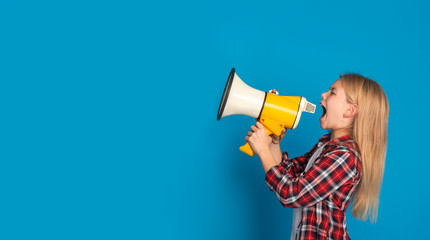 Emotional little girl shouting at copy space with megaphone, making announcement