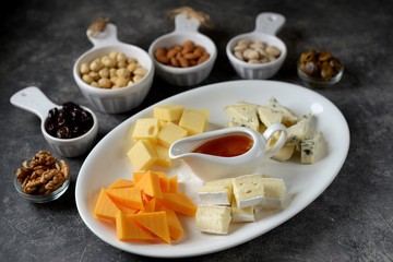 Various types of cheeses with olives, nuts, fruits and honey. Appetizer for a wine party.
