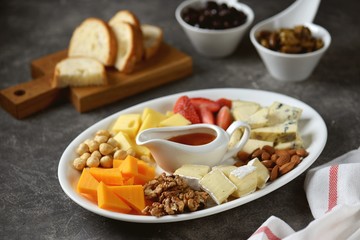 Various types of cheeses with olives, nuts, fruits and honey. Appetizer for a wine party.
