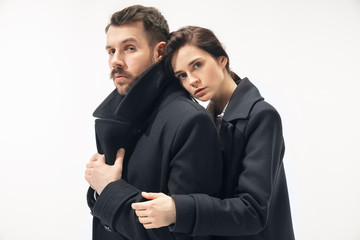 Warmth. Trendy fashionable couple isolated on white studio background. Caucasian woman and man posing in basic minimal black stylish clothes. Concept of relations, fashion, beauty, love. Copyspace.