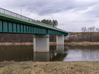 Fototapeta na wymiar landscape with green bridge over slow flowing river
