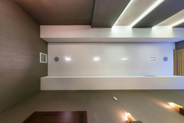 looking up on suspended ceiling with halogen spots lamps and drywall construction in empty room in apartment or house. Stretch ceiling white and complex shape.