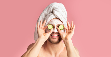 Guy with mask on face applies cucumber to eyes