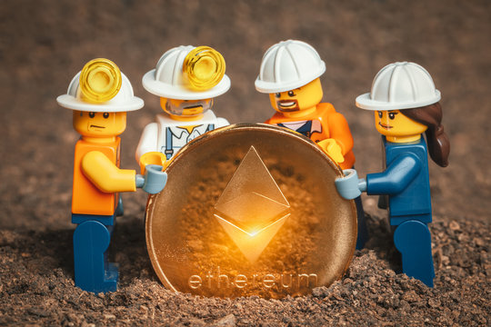 ANKARA, TURKEY. NOVEMBER 17, 2019. Group of Lego mini miner figurines holding shiny ethereum together and posing.  Cryptocurrency, blockchain and mining concept.