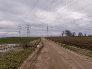 Fototapeta na wymiar landscape with wet earth road and high voltage line