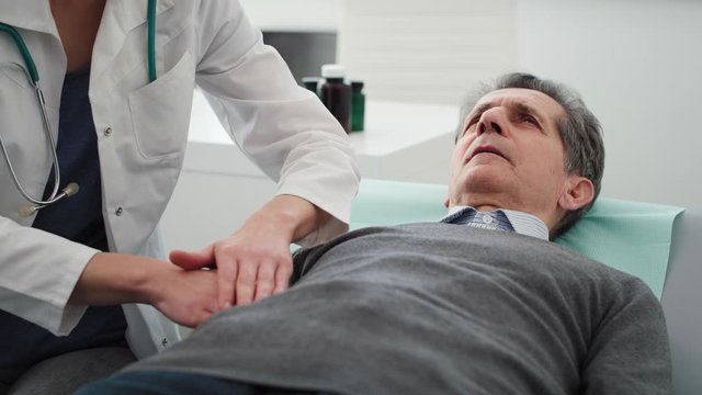 Handheld video shows of doctor examining stomach of senior man. Shot with RED helium camera in 8K