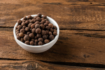 Allspice in bowl on vintage wooden background. Close up