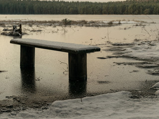 landscape with flooded lake shore, picnic area covered with ice