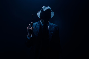 Silhouette of gangster raising gun on dark blue background - obrazy, fototapety, plakaty