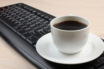 Fototapeta na wymiar Ceramic cup with coffee and a computer keyboard on a wooden table