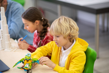 Obraz premium Boy playing with buildable bird, girl making notes