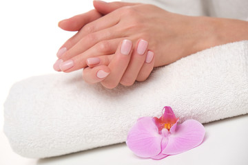 Obraz na płótnie Canvas Beuatiful delicate manicure on female hands. The picture of hands lying on the white towel with purple orchid.