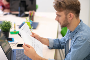 Male teacher sitting at laptop, checking grammar test