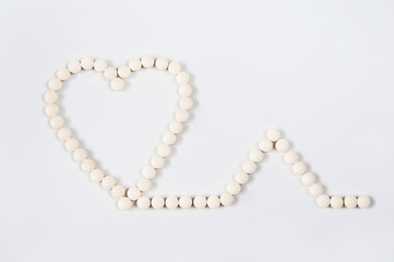 Obraz premium Medicine pills concept on gray background. Round pills in the shape of a heart on a white background close-up and copy space.