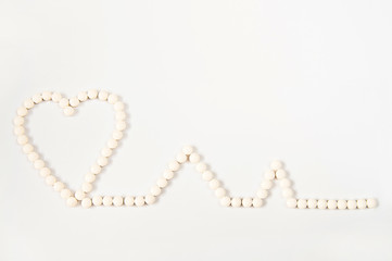 Medicine pills concept on gray background. Round pills in the shape of a heart on a white background close-up and copy space.