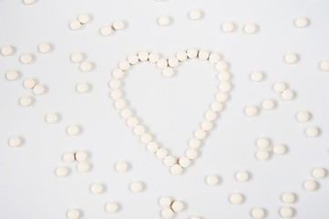 Medicine pills concept on gray background. Round pills in the shape of a heart on a white background close-up and copy space.