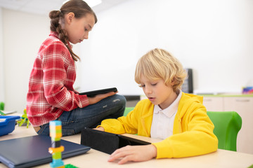 Pupils sitting with tablets, carefully reading something