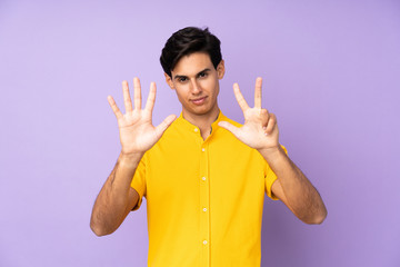 Man over isolated purple background counting eight with fingers