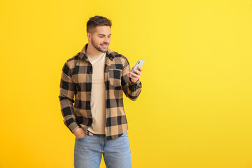 Young man with mobile phone on color background