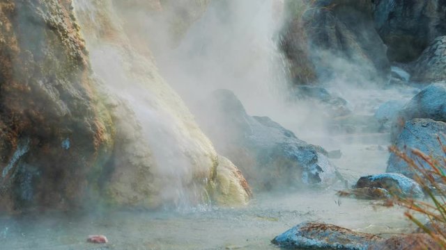 Hot spring in Thailand. Flowing water forms mineral growths emitting heavy smoke. Average shot. Half slow motion.