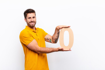 young handsome man excited, happy, joyful, holding a number 0.