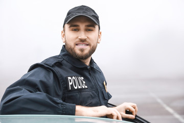 Male police officer near car outdoors