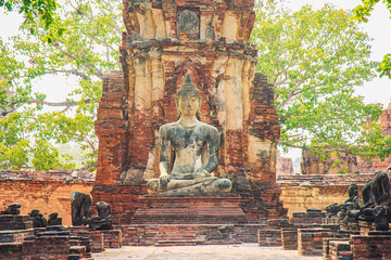 An old Buddha statue in ancient ruin with nature background at Wat Mahathat