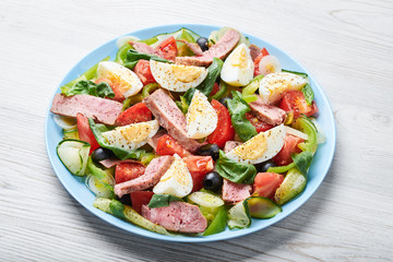 Blue plate with classic nicoise salad. Close-up.
