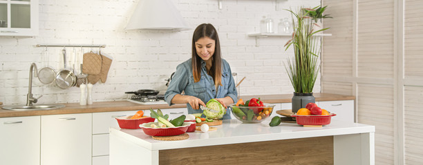 A young woman is preparing a salad in the kitchen .